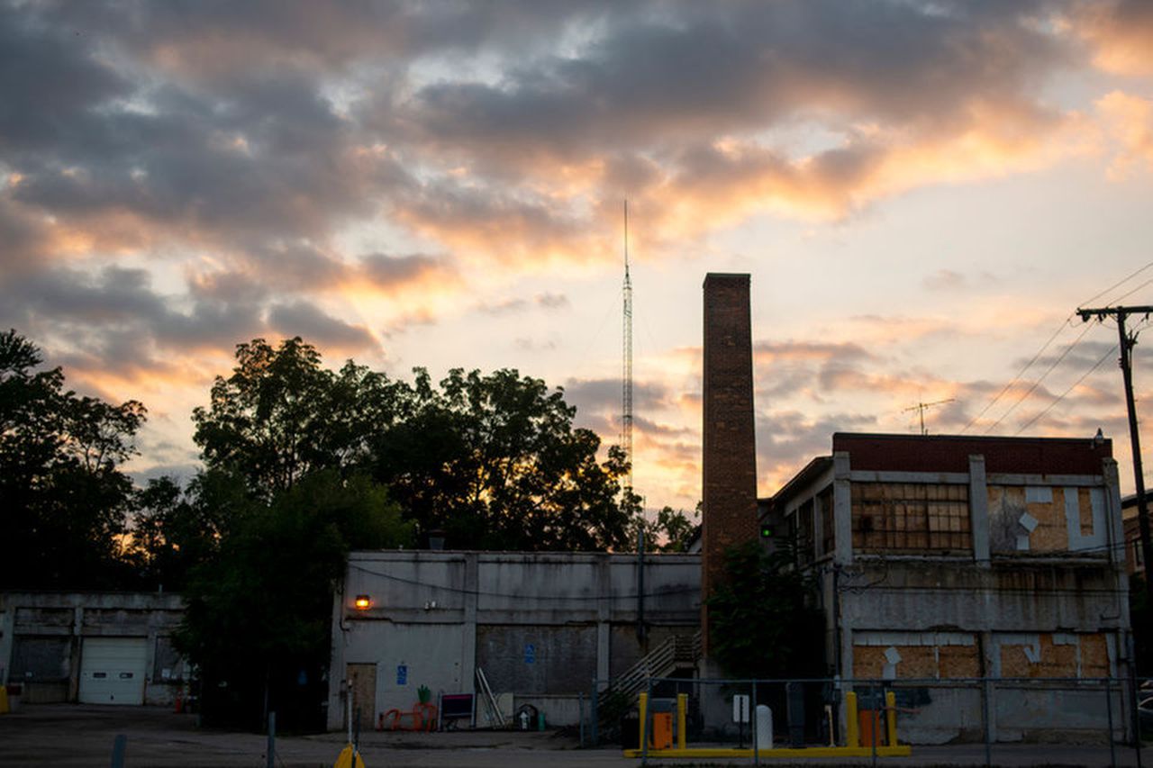 Photograph of 415 W Washington St in Ann Arbor, a dilapitated two story brick warehouse structure with a tall brick chimney, at sunset
