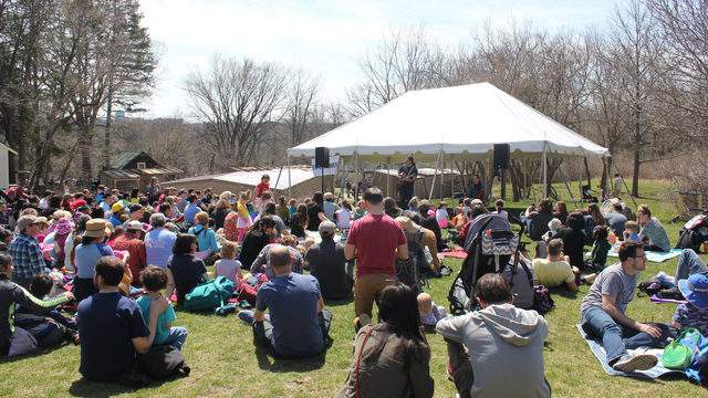 Photo of the Earth Day event at Leslie Science Center showing a large crowd composed of families on an expansive green lawn 