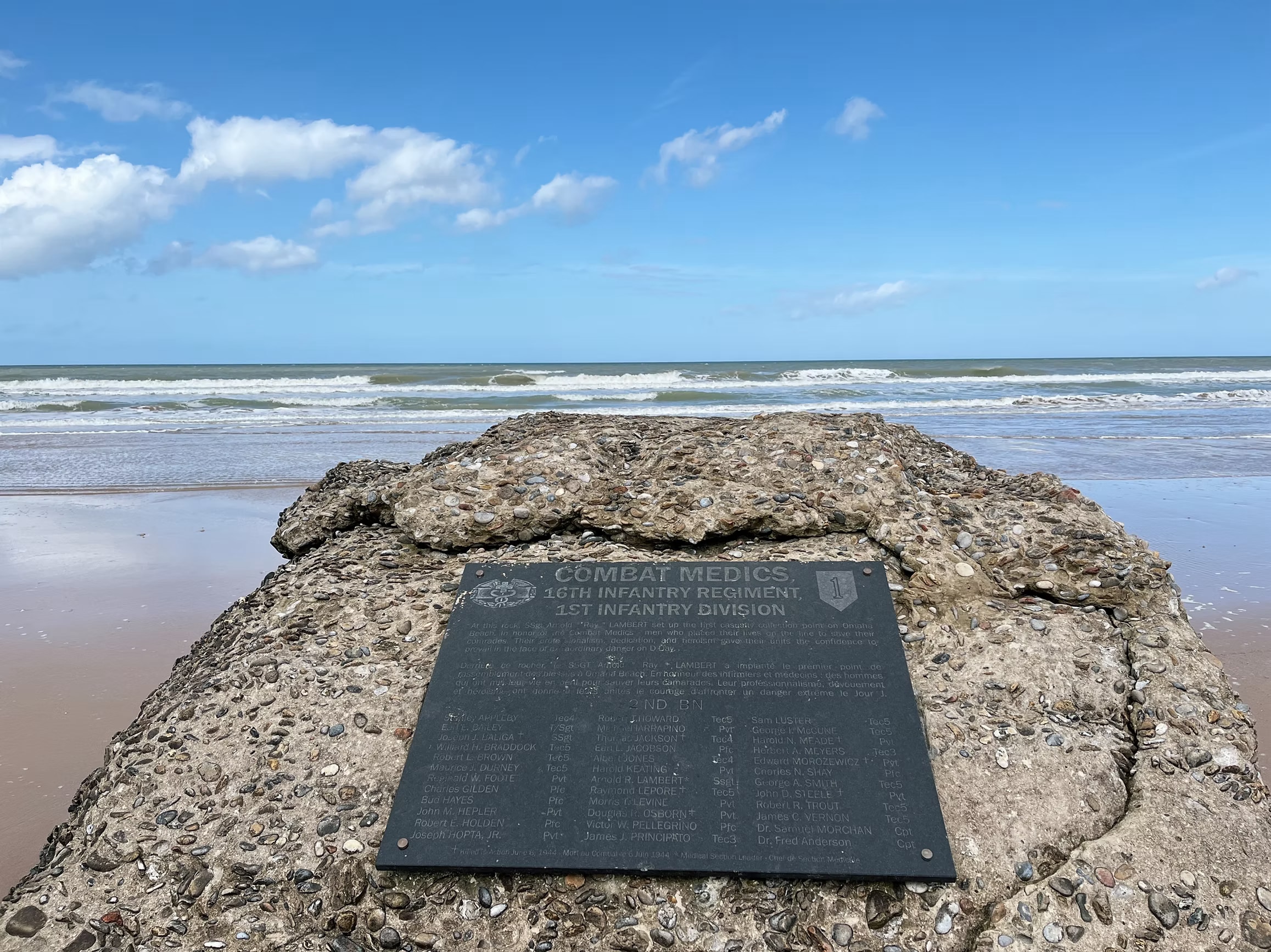 Photo of memorial plaque on a rock on Omaha Beach in Normandy listing the names of the combat medics of the 2nd battalion of the 16th regiment of the 1st division who served that day.